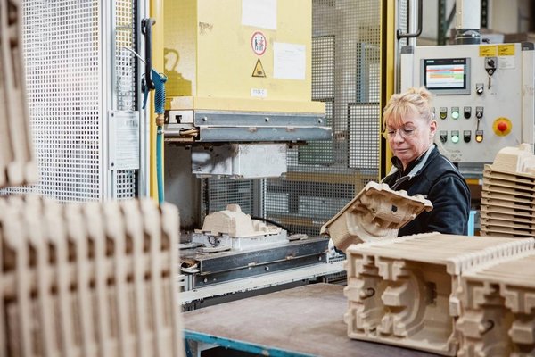 Miarbeiterin bedient Presse zur Herstellung eines PressTec Fasergussteils